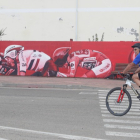 Un ciclista pasa por delante del mural alusivo a la Vuelta a España 2023 situado en la calle Julio Hernández de La Bañeza. RAMIRO