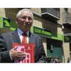 El presidente de Caja Segovia, Atilano Soto, con el documento del SIP aprobado ayer, ante una sucurs