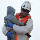 Un sanitario lleva en brazos a un bebé rescatado en una patera, en Málaga.