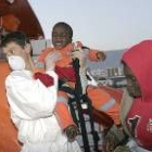 Un miembro de la Cruz Roja desembarca a uno de los bebés que navegaba en una patera en Motril