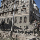 Dos rebeldes yemeníes inspeccionan las ruinas de edificios destruidos por los bombardeos en Saná.
