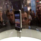 Varios aficionados a las últimas tecnologías contemplan un móvil de la marca Apple.