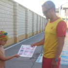 Un niño recibe el díptico donde se recogen las normas básicas para el medio acuático.