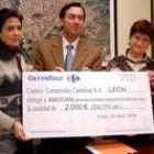 El director de Carrefour en León, Antonio Márquez , hace entrega del cheque a Amidown