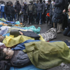 Decenas de ucranianos muestran sus respetos a un grupo de personas muertas durante los disturbios que tuvieron lugar ayer en Kiev.