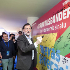 Mariano Rajoy firma en un panel acompañado por el presidente del PP del País Vasco, Alfonso Alonso. DAVID AGUILAR
