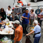 Venezolanos hacen cola para pagar la fruta y las verduras en un mercado callejero, en Caracas, el 13 de noviembre.