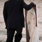 Un empleado transporta el retrato del papa en el vestíbulo Nervi.