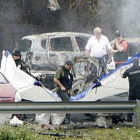 Agentes de la Erzaintza cubren los restos del vehículo del inspector asesinado.