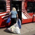 Una mujer evacuada sube a un autobús con sus pertenencias
