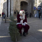 Un judíos ultraortodoxo observa con descontento a un palestino disfrazado de Papá Noel que reparte árboles.