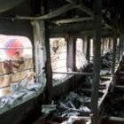 Dos hombres miran por la ventana de uno de los vagones afectados, que quedó completamente destruido