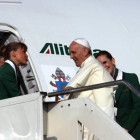 Una azafata da la bienvenida al Papa al subir a bordo del avión que le traslada a Brasil.