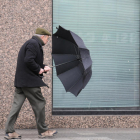 Un hombre sujeta su paraguas durante una tacha de viento. DL