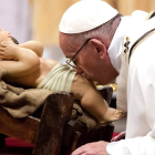 El papa besa la figura del niño Jesús durante la misa de Navidad en el Vaticano. CLAUDIO PERI
