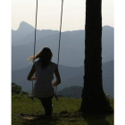 Una mujer mira al horizonte sentada en un columpio.