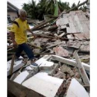 Un superviviente del terremoto camina entre los escombros de su casa