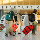 Varios pasajeros cargan con sus maletas por los pasillos de un aeropuerto.