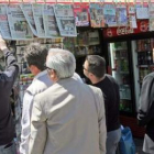 Un grupo de personas lee las portadas de los periódicos en un quiosco de Atenas.