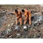 Dos operarios trabajan limpian los escombros del avión.