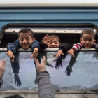 Niños saludan desde un autobús con destino a Serbia. G. LICOVSKI