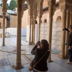 Unos turistas fotografían el Patio de los Leones de la Alhambra de Granada.