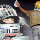 Un obrero limpia un cartel con la fotografía del piloto español de Fórmula Uno, Fernando Alonso