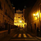 Vista nocturna de la calle Portería, iluminada por una farola, y la catedral.