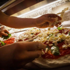 Un restaurante de comida rápida prepara pizzas para llevar a casa. CÉSAR ABBATE