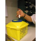 Una enfermera deposita una aguja en un contenedor especial