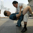 Una pareja de chinos  bailan en una plaza de la ciudad de Shanghai