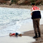 El niño sirio Aylan Kurdi, ante un guardacostas en la playa de Turquía a la que llegó su cadáver.