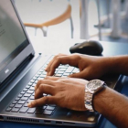 Un hombre escribe en un ordenador portátil.