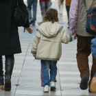 Unos padres pasean con su hijo, cogidos de la mano.