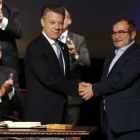 Santos (izquierda) y Rodrigo Londoño, alias 'Timochenko', se dan la mano tras firmar el nuevo acuerdo, en Bogotá, este jueves.