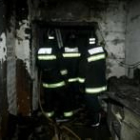 Tres bomberos comprueban el estado de la casa incendiada en la calle Cornatel