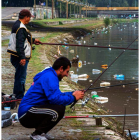Ds hombres pescan en el río Vardar, cubierto de botellas y basura. GEORGI LICOVSKI