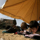 Niños palestinos asisten a clase en una tienda instalada entre los restos de su escuela destruída.