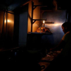 Una mujer usa la luz de una linterna para trabajar en la cocina de un restaurante tras un nuevo apagón en Caracas.