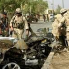 Soldados de EE.UU. contemplan los restos de un coche bomba en Bagdad