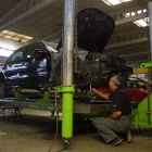 Un hombre trabaja en el arreglo de un vehículo en un taller de coches. ANA F. BARREDO