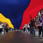 Un grupo de ciudadanos porta una bandera venezolana gigante, este domingo en Caracas, durante la marcha contra el Gobierno.