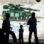 Niños palestinos juegan ante una pintada alusiva a la guerra contra Israel