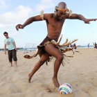 Un niño africano juega con un balón en la playa.