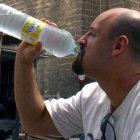 Un hombre bebe de una botella de agua mineral.