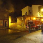 El inmueble afectado humea, mientras un bombero, desde el tejado, vigila posibles rebrotes.