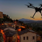 Silueta de un dron volando sobre una antigua ciudad europea.