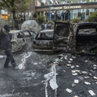 Un hombre camina junto a una hilera de coches carbonizados tras unos disturbios en mayo del 2013, en un suburbio de Estocolmo.