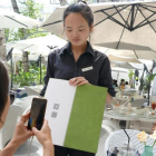 Una joven paga su consumición en un terraza de Shanghái con el teléfono móvil.