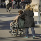 Una mujer acompaña a otra en silla de ruedas en Barcelona.